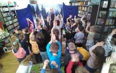 Dzieci stoją z podniesionymi rękoma w g&oacute;rze i naśladują aktora. 