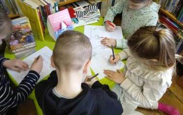 Dzieci przy okrągłym stoliku zaznaczają na kartce drogę w labiryncie do chorej babci.