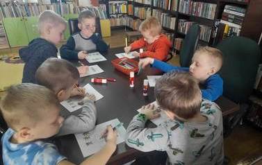 Przy stoliku siedzą chłopcy i zaznaczają na kartkach dr&oacute;żki świnek do swoich domk&oacute;w. Chodzi o bajkę pt "Trzy małe świnki"