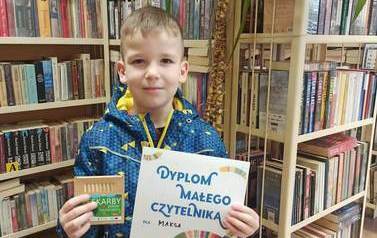 Chłopiec trzyma w ręku dyplom i kredki.