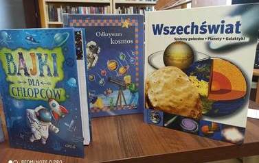 Na stole stoją pionowo książki o kosmosie.