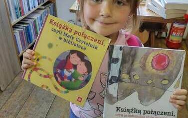 Dziewczynka w kapelusiku trzyma dwie książki z wyprawki czytelniczej.