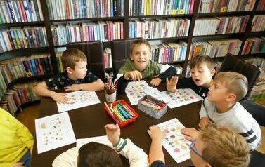 Chłopcy przy stole wykonują karty pracy o jesieni.