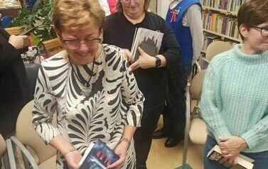 Czytelnicy podchodzą z zakupionymi książkami po autograf do pisarza.