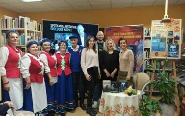 Zdjęcie grupowe czytelnik&oacute;w z autorem, niekt&oacute;rzy są przebrani w stroje kociewskie.