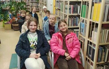 Dzieci siedzą na krzesłach przodem do telewizora.