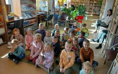 Dzieci siedzą na dywanie i słuchają bajki.