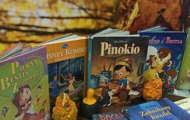 Wyłożone na stole z widocznymi tytułami książki produkcji Walta Disneya, w tle obraz jesieni. Pomiędzy książkami  są położone małe dynie.