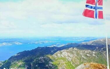 Widok na g&oacute;ry, morze i flagę w Norwegii. Obraz wyświetlany na dużym ekranie podczas koncertu.