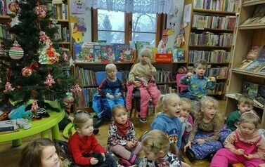 Grupa dzieci siedzących na siedziskach i krzesełkach przy choince w Borzechowie