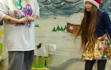 Dzieci patrzą na teatrzyk. Widać dziewczynke w mikołajkowej czapce i Panią przebraną za renifera.