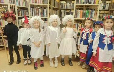 Kolędnicy stoją w grupie i śpiewają kolędę. Niket&oacute;re dzieci mają ubrany str&oacute;j kociewski.