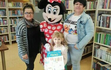 Nagrodzona dziewczynka stoi z przebraną Myszką Minnie, bibliotekarką i Panią Anią.