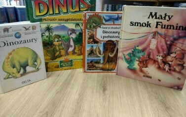 Na biurku wystawione są pionowo książki o dinozaurach  z widocznymi tytułami.