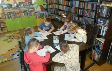 Dzieci siedzą przy stole i robią karty pracy.