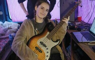 W busie dziewczyna trzyma gitarę elektryczną, a za Nią stoi uśmiechnięta Iwona Skwarek.