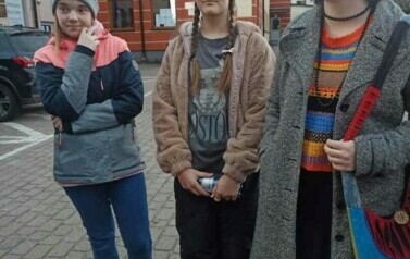 Trzy dziewczynki stoją na dworzu przy Urzędzie Gminy.