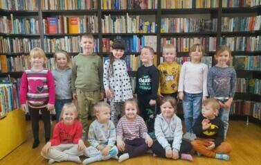 Zdjęcie grupowe dzieci na tle p&oacute;łek z książkami.