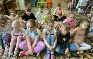 Na dywanie siedzi grupa dzieci.