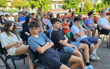 Publiczność siedzi na krzesłach i słucha Czytających.