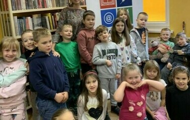 Dzieci stoją w grupie razem ze swoją wychowawczynią w bibliotece w Zblewie.