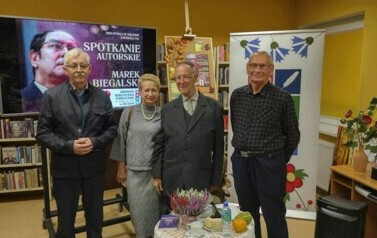 Trzech czytelnik&oacute;w stoi razem z Panem Markiem przy stoliku.