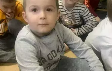 Dzieci siedzą  na siedziskach  w bibliotece.