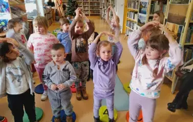 Dzieci stoją obok siebie i śpiewają piosenkę, ktorą się nauczyły na Dzien Babci i Dziadka z pokazywaniem rączkami.