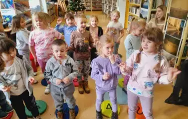Dzieci stoją obok siebie i śpiewają piosenkę, ktorą się nauczyły na Dzien Babci i Dziadka z pokazywaniem rączkami.