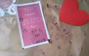 Na brązowym papierze są przyczepione serduszka i kartka z tekstem zachęcającym do podarowania bibliotece książki kt&oacute;rej już nie potrzebujemy.