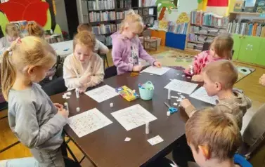 Dzieci przy stole uzupełniają zwierzątkowe sudoku naklejając odpowiednie elementy w puste kwadraciki.