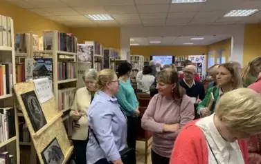 Biblioteka pełna Czytelnik&oacute;w rozmawiających ze sobą.