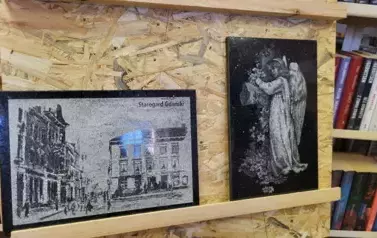 Na stojaku dwa obrazy z granitu przedstawiające stare miasto Starogard Gdański, a na drugim postać anioła.