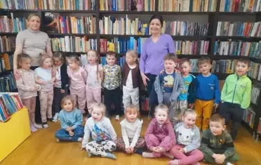 Dzieci stoją w grupie razem z Panią wychowawczynią i z bibliotekarką.
