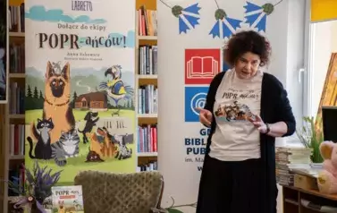 Anna Sakowicz stoi przed dziećmi i opowada.
