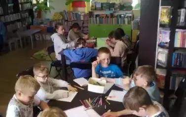Dzieci przy stołach wypełniają karty pracy.