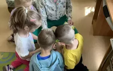 Przy Pani Małgorzacie usiadło czworo dzieci aby zobaczyć obrazki w książeczce