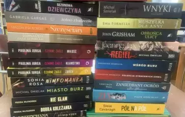 Na stole w dw&oacute;ch rzędach leżą pionowo poukładane nowe książki
