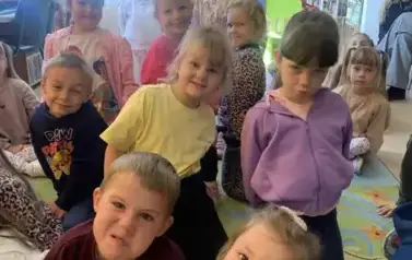 Dzieci na dywanie pozują do zdjęcia.