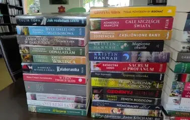 Na stole z bliska widoczne dwa rzędy nowych książek z widocznymi tytułami.