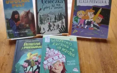 Na stole jest położone pięć nowych bajek dla dzieci z widocznymi tytułami.