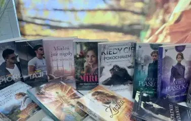Rozłożone nowe książki z widocznymi tytułami, w tle jesienny pejzaż