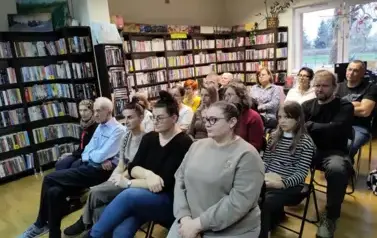 Duża grupa czytelnik&oacute;w siedząca na krzesłach  z dobrze widocznymi twarzami.