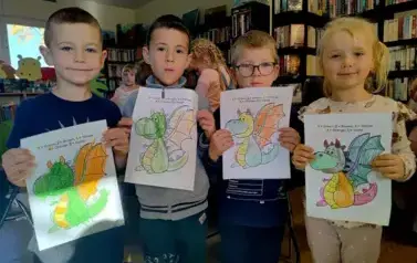 Troje chłopc&oacute;w i jedna dziewczynka pokazują swoje pokolorowane smoki.