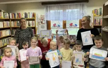 Dzieci stoją razem ze swoją Panią i z Panią z biblioteki. Pokazują swoje prace plastyczne, narysowaną postać z bajki.