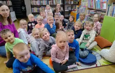 Dzieci siedzą na siedziskach i słuchają bajki.