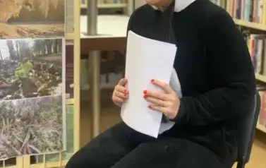 Na krześle siedzi kobieta przebrana w misia Pandę i trzyma kartki.