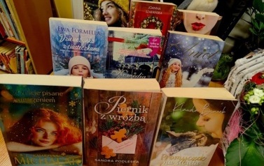 Na biurku są wyłożone na podp&oacute;rkach książki o tematyce świątecznej