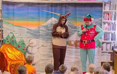 Na środku stoją przebrani renifer i elf i rozmawiają ze sobą. W tle zaśnieżony g&oacute;rski pejzarz.