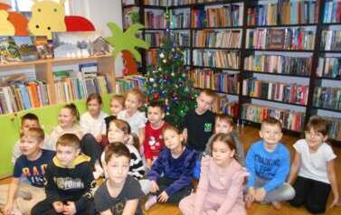 Wszystkie dzieci siedzą przy choince.